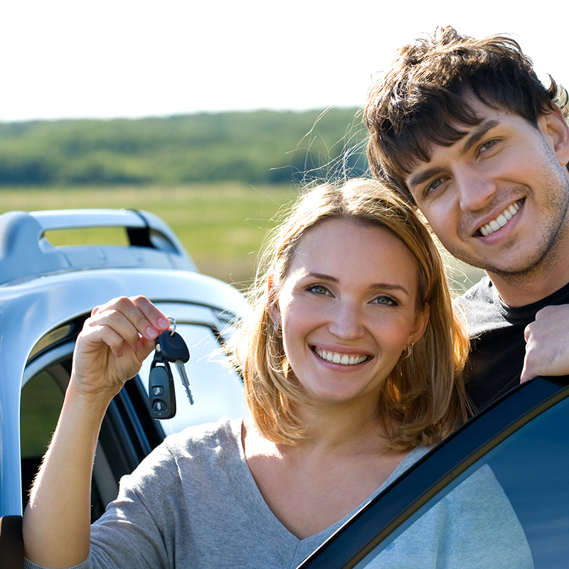 a young couple with keys to a new car