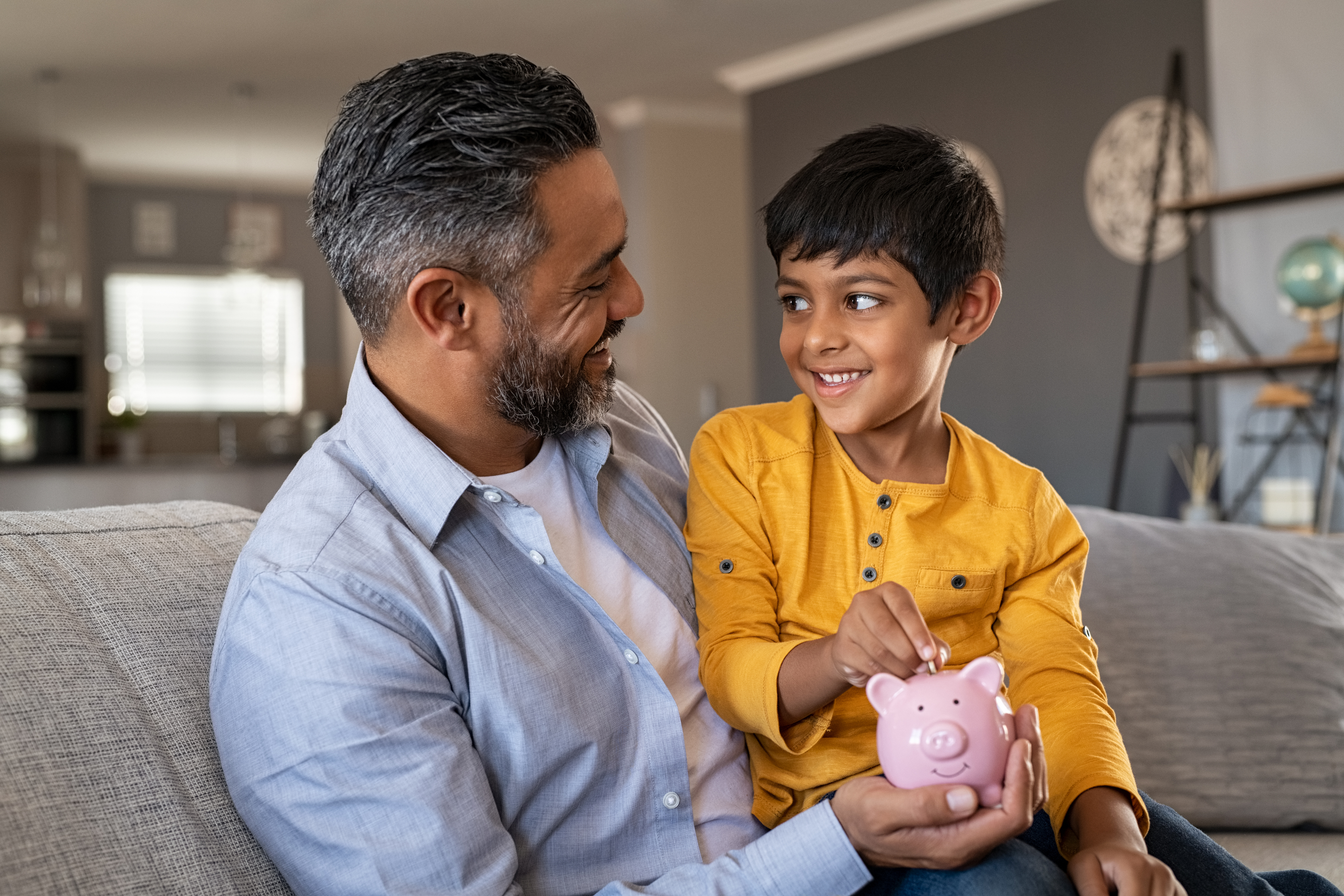 a father and son holding a piggy bank