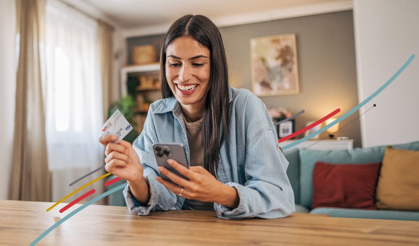 a lady looking at her phone and holding a Tech CU credit card
